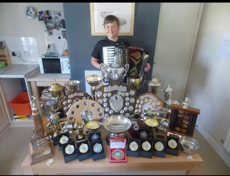 Kyle with a selection of his solo accordion competition trophies aged 14, 2015.